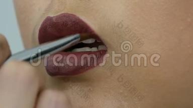 专业造型师化妆师用特殊的画笔画出深红色的嘴唇用亚洲女孩模特的特殊画笔